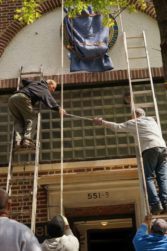 Silas and Ray pass a tool between two ladders